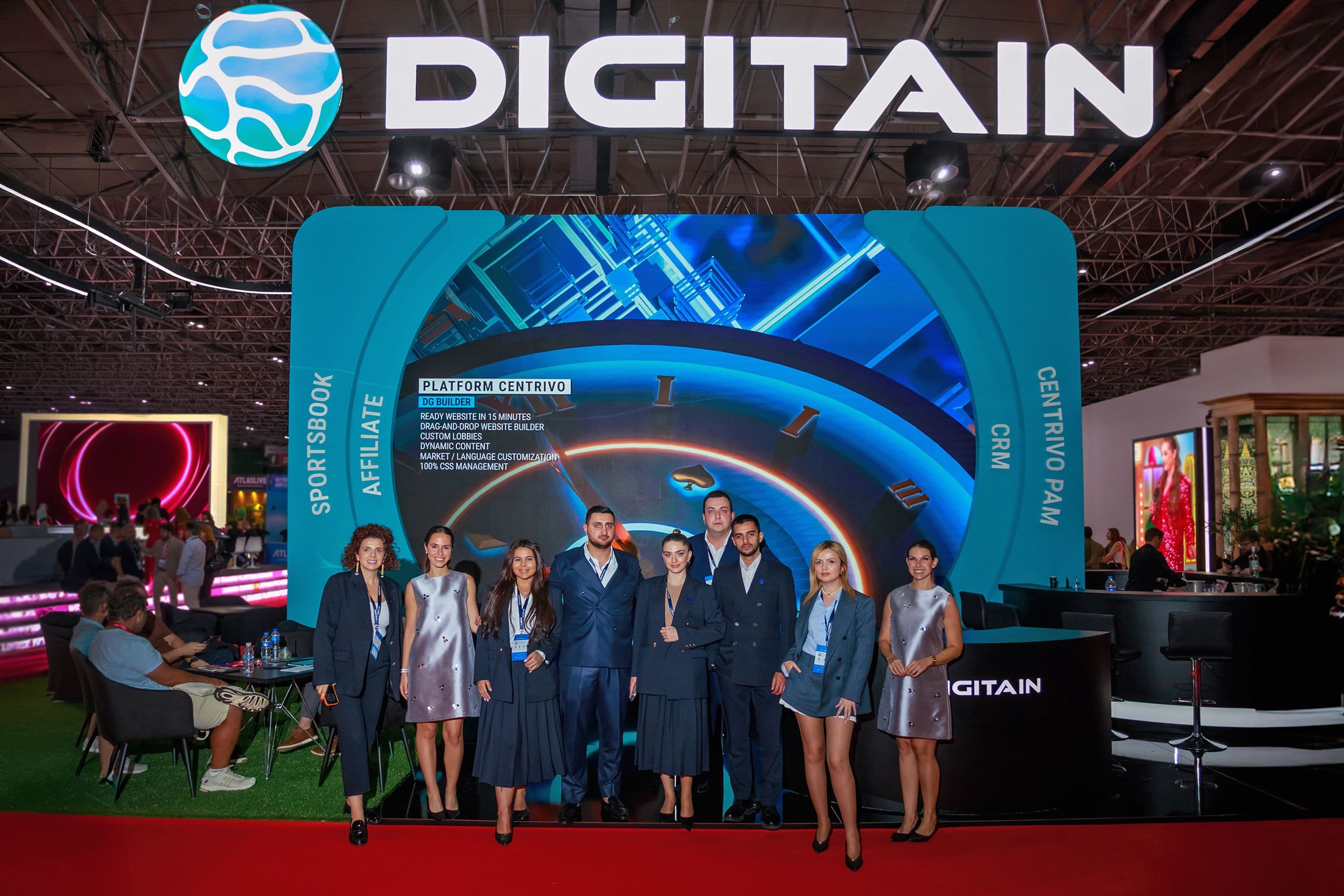 Digitain team poses in front of their large, modern exhibition booth at a trade show.