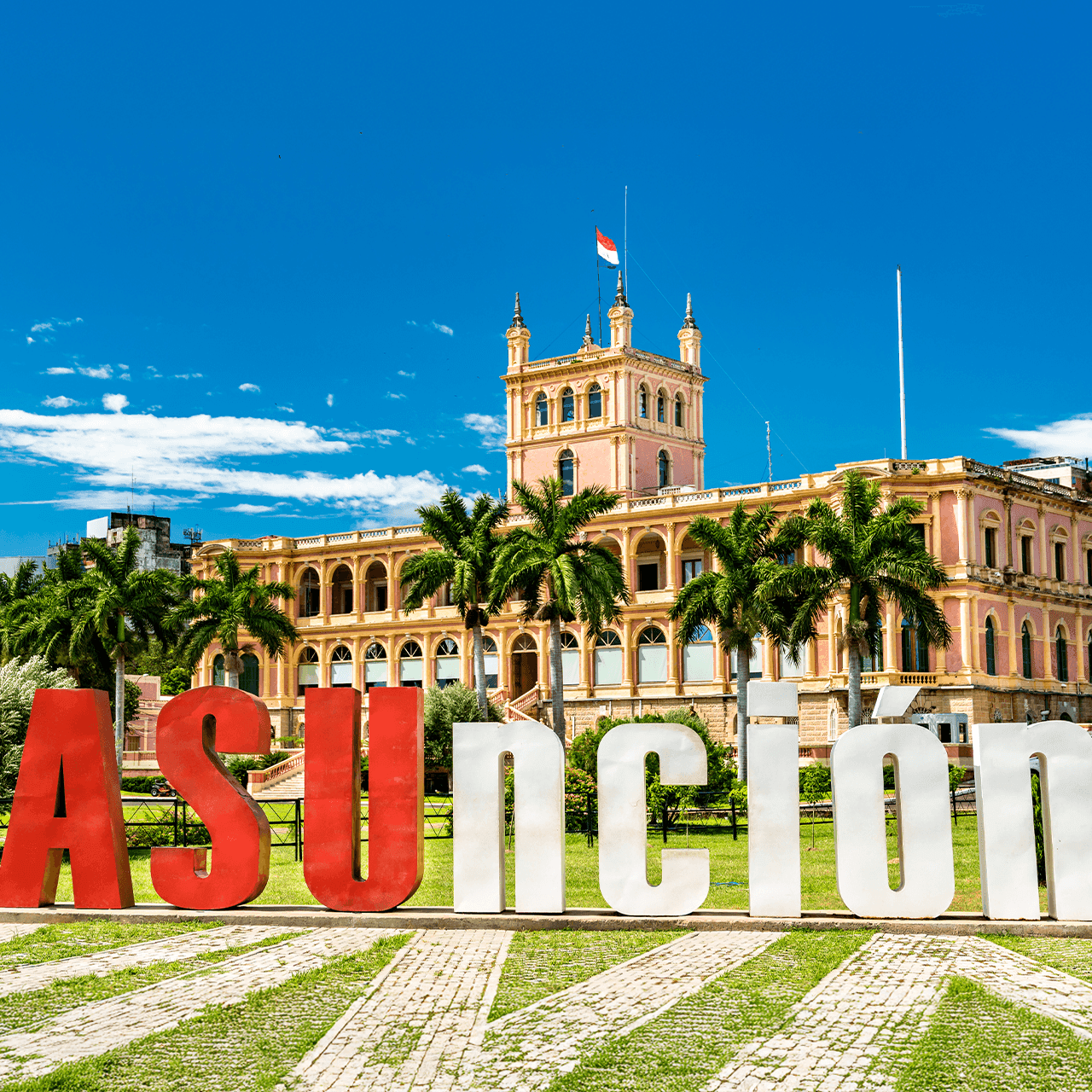The Presidential Palace in Asunción, Paraguay, with large 'ASUNCION' letters and palm trees.