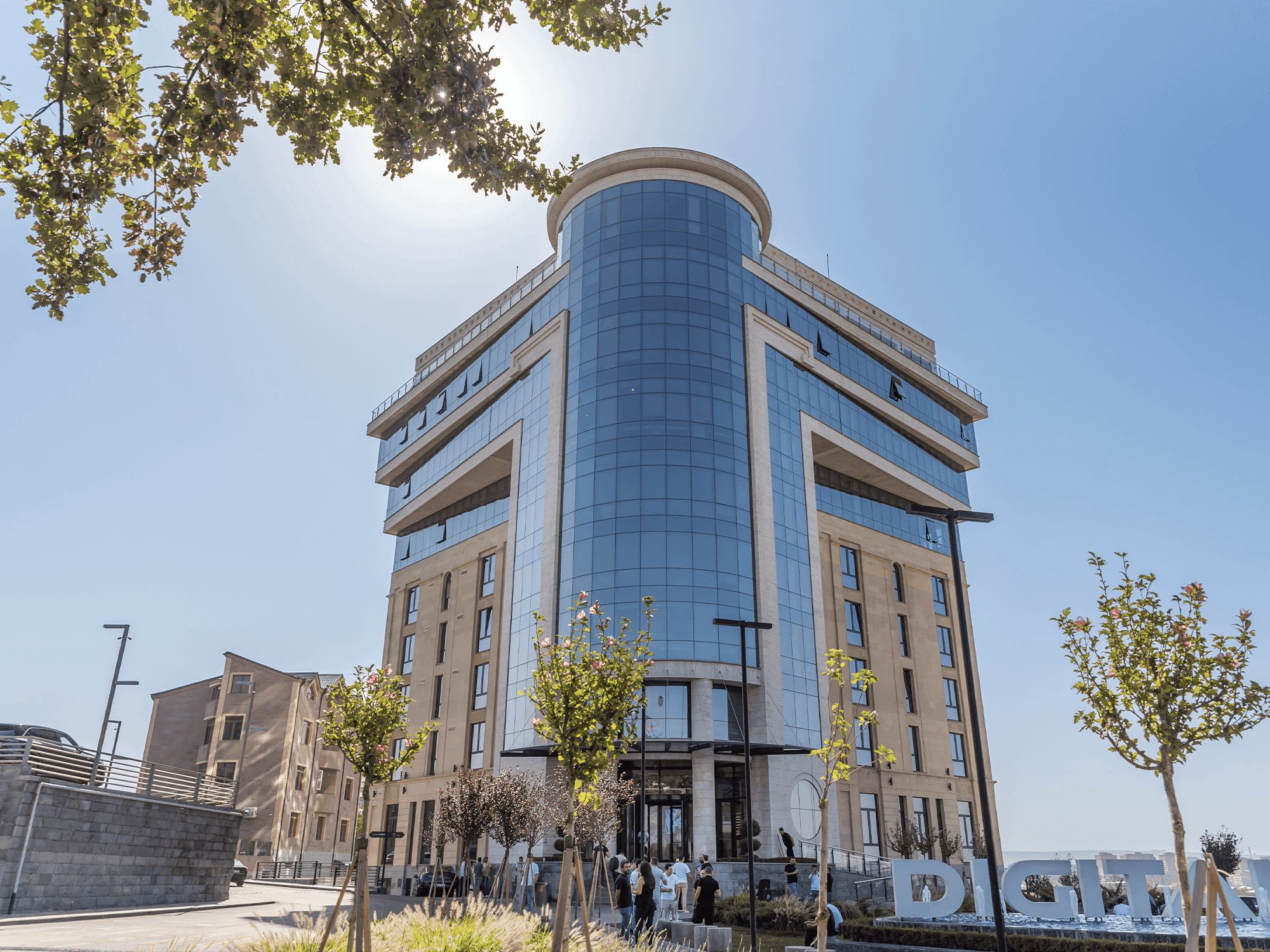 Modern building with curved glass and stone facade under bright blue sky.