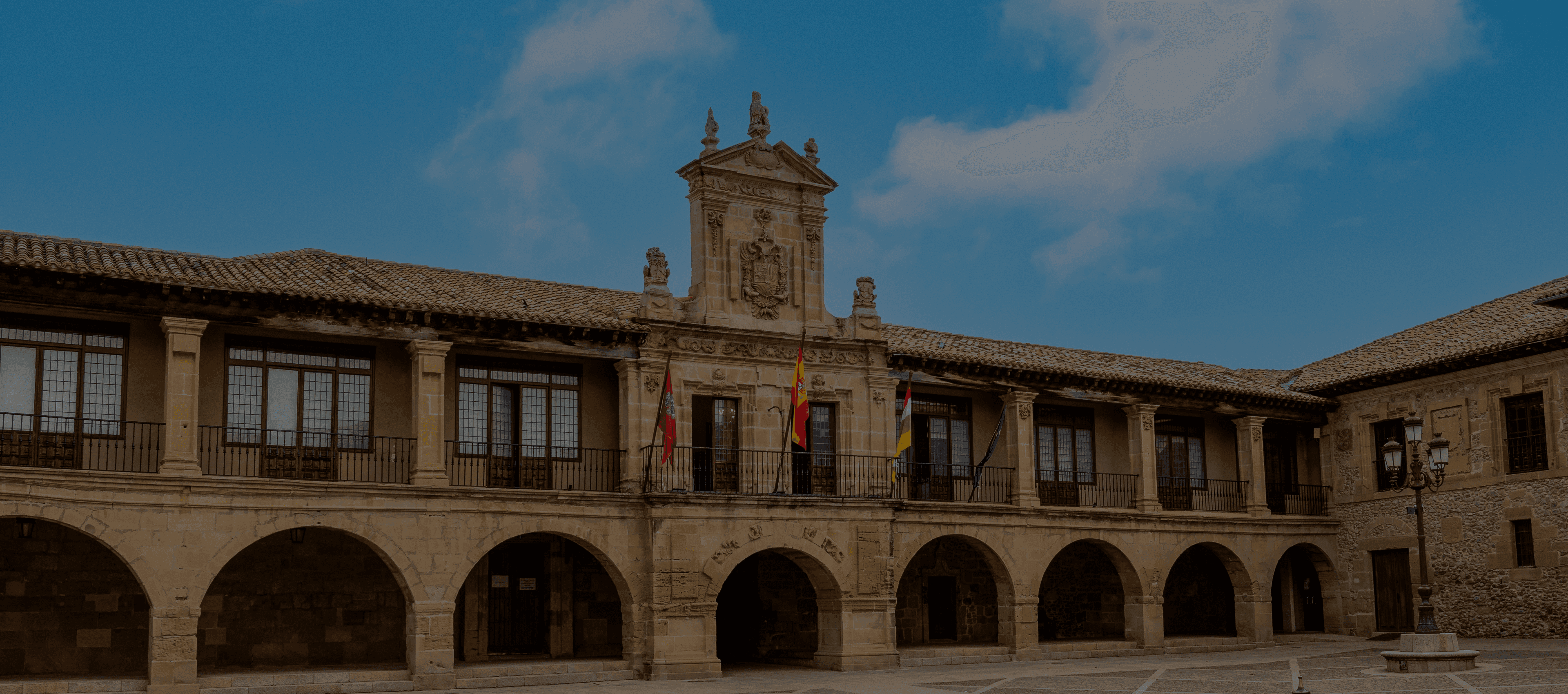 Historic stone building with arched ground floor, windows, and ornate facade under a blue sky.